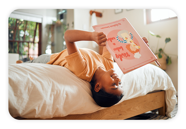 a boy reading a book on his bed