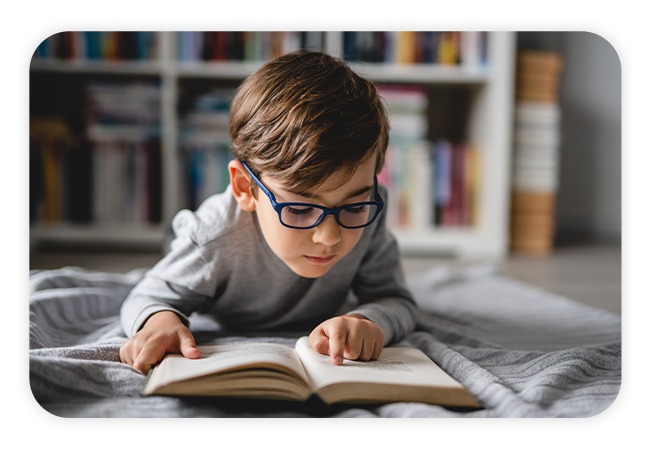 a little boy reading a book on the living room floor