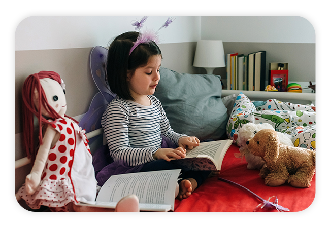 a little girl reading a book to her stuffed animals