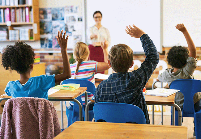 children raising their hands in a classroom