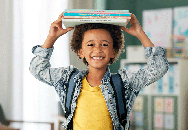 a child holding a small stack of books over their head
