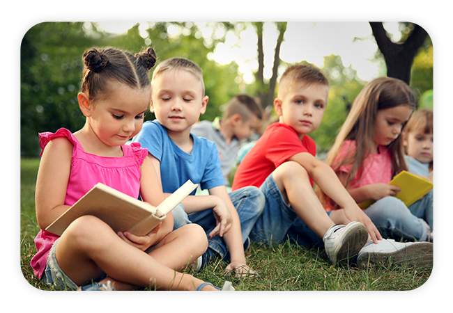 children reading outside in a grassy lawn