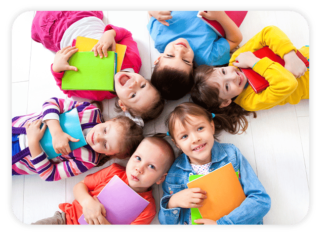 kids laying on their backs in a circle with their heads together, each clutching a handful of books