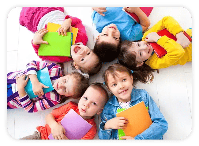 kids laying on their backs in a circle with their heads together, each clutching a handful of books